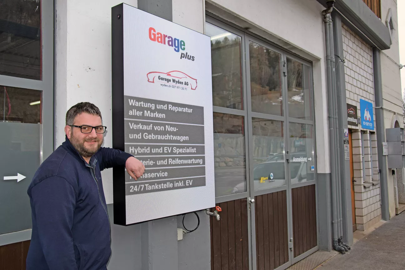 Der CEO: Andreas Wyden vor der Garage und neben der Dienstleistungstafel.